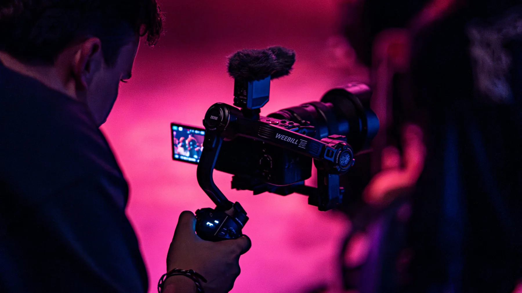 Caméra sur stabilisateur pendant un tournage, sous une lumière rose